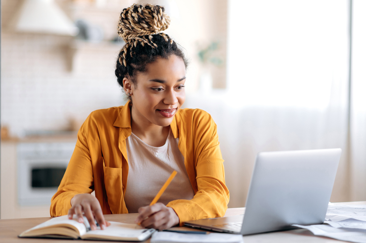 Young woman on laptop taking notes