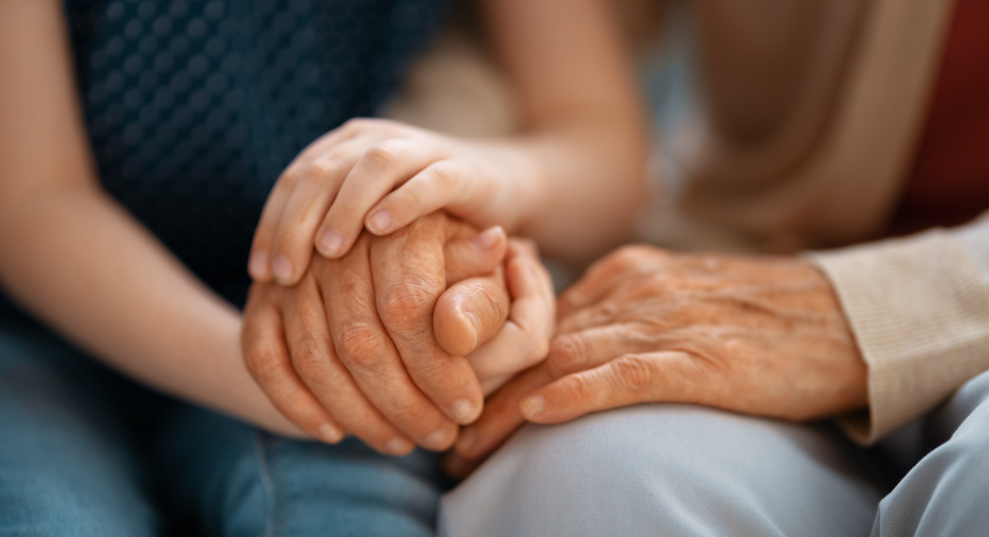 An older person and younger person hold hands