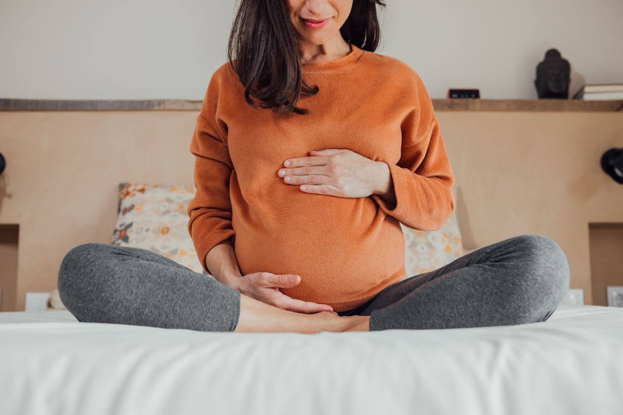 Pregnant woman sitting on bed