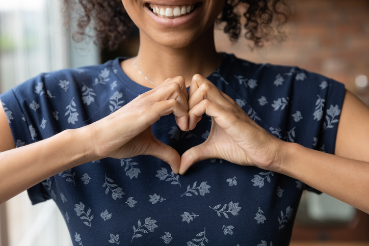 Smiling woman makes heart shape with her hands