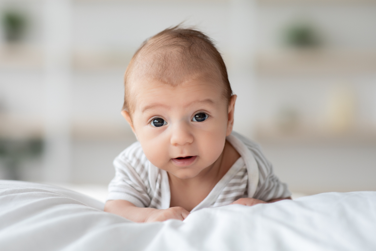 Baby on tummy looking at camera