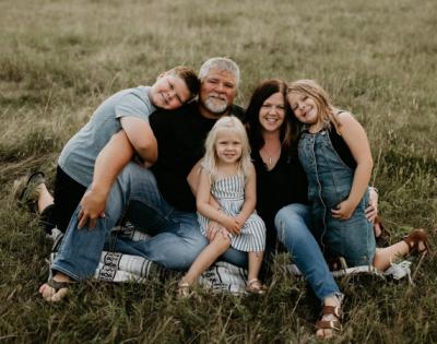 Family with parents and three kids sitting happily in a field