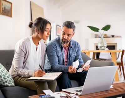 A man and a woman looking at a computer screen and piece of paper to plan a budget
