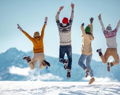 family dressed in winter clothes jumping in the air