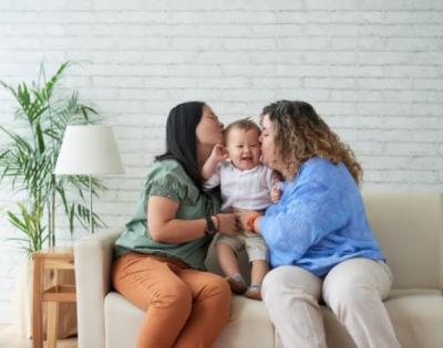 Two women holding a baby and kissing the baby on either cheek