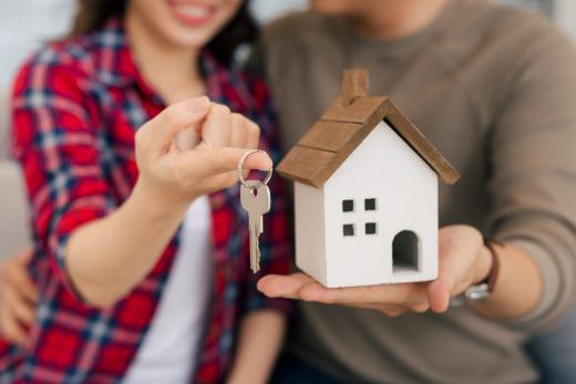 Couple holding a house key and small house