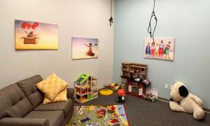 Play therapy room filled with a toy kitchen, dollhouse, playmat and couch.