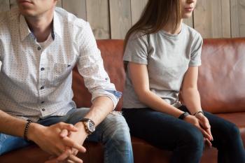 Man and woman sitting apart on a couch