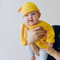 Baby in bright yellow hat and sweater with heart of face