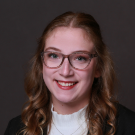 Headshot of Rachel Fischer, a white woman with glasses and curled, medium brow hair