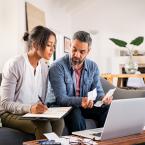 A man and a woman looking at a computer screen and piece of paper to plan a budget
