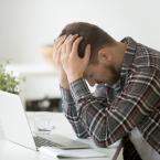 Man sitting at a computer with head in hands looking distressed