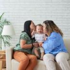 Two women holding a baby and kissing the baby on either cheek