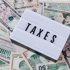the word "taxes" on a marquee letterboard with money in the background