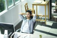 Man sitting at desk with arms behind his head in a relaxed position