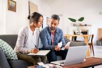 A man and a woman looking at a computer screen and piece of paper to plan a budget