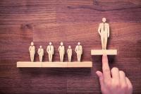 row of wooden business people with leader lifted up