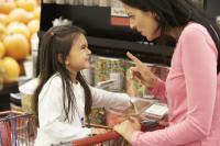 greedy child in supermarket cart with mom scolding her