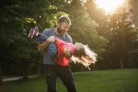 dad playing with daughter by swinging her around outside