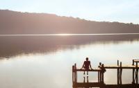 Person sitting on a dock overlooking a peaceful lake