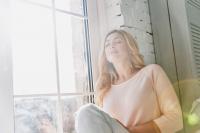 woman sitting in the light of a window looking relaxed