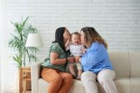 Two women holding a baby and kissing the baby on either cheek