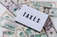 the word "taxes" on a marquee letterboard with money in the background
